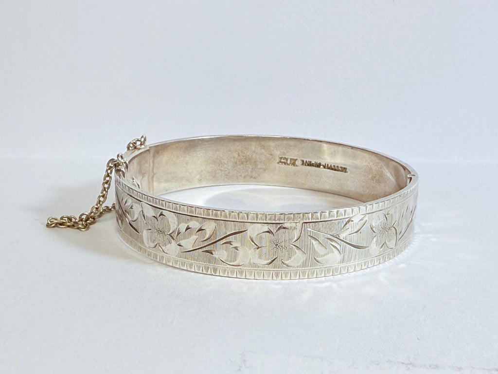 Silver bracelet with intricate designs on a white background