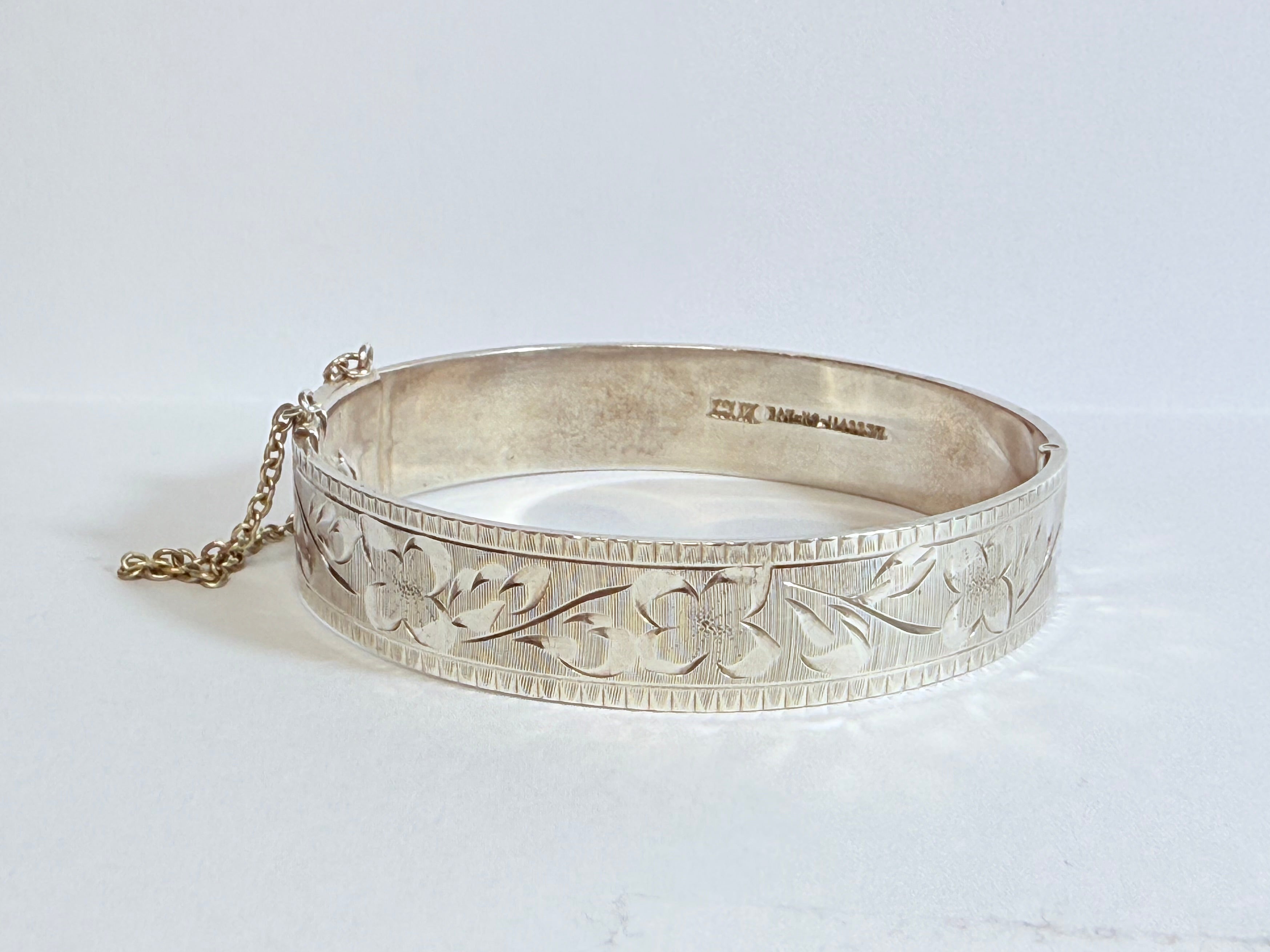 Silver bracelet with intricate designs on a white background